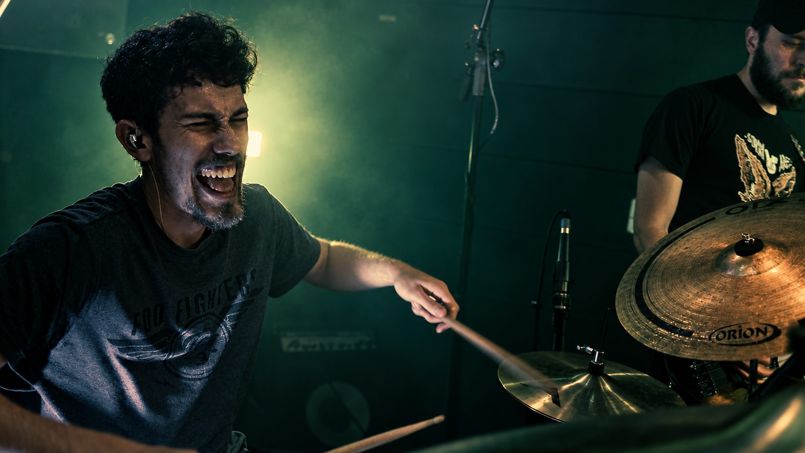 Baterista tocando com intensidade sob luz verde